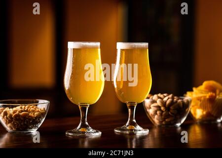 Spuntini croccanti per il cliente. Due bicchieri di birra leggera e patatine e noci al bar Foto Stock