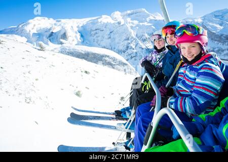 Gruppo di bambini amici di sci siedono sulla seggiovia che solleva sulla cima della montagna in giornata di sole Foto Stock