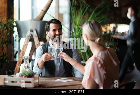 Felice coppia seduta al coperto nel ristorante, bicchieri da clinking. Foto Stock