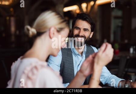 Felice coppia seduta al coperto nel ristorante, che parla. Foto Stock