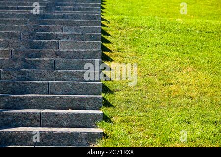 Scale in pietra e prato, primo piano. Gradini grigi e erba nel parco, frammento. Foto Stock