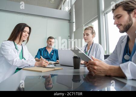 Team medico che discute delle opzioni di trattamento con i pazienti. Gruppo di medici che si riunita nella sala riunioni. Foto Stock