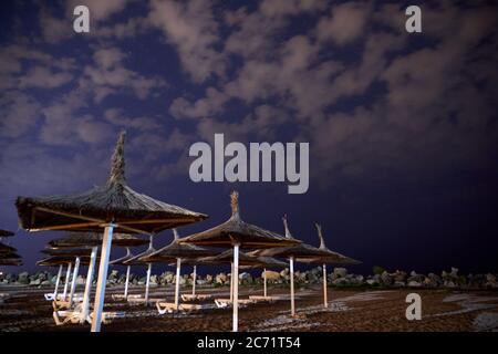 Ombrelloni sulla spiaggia di notte con nuvole e stelle sul cielo Foto Stock