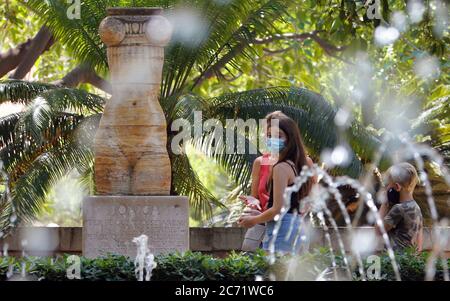 Palma, Spagna. 13 luglio 2020. Le ragazze indossano protettori per bocca e naso nel giardino dei Jardins del Rei. A Maiorca e nelle altre isole Baleari, lunedì 13.07.2020 è entrato in vigore un ampio obbligo di mascheramento a causa della pandemia di Corona. Indossare una maschera sopra la bocca e il naso è quindi obbligatorio praticamente ovunque fuori dalle proprie quattro pareti, anche se una distanza di sicurezza per le altre persone può essere mantenuta. Chi non rispetta l'obbligo di mascheramento rischia una multa di 100 euro. Credit: Clara Margais/dpa/Alamy Live News Foto Stock