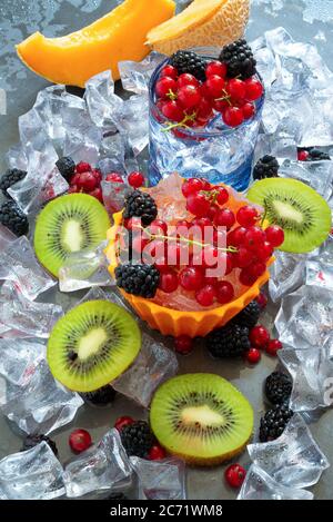 sete il bicchiere dissetante con acqua fredda e frutta fresca estiva con ghiaccio Foto Stock