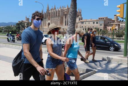 Palma, Spagna. 13 luglio 2020. I giovani indossano protettori per bocca e naso quando camminano per Palma di Maiorca. A Maiorca e nelle altre isole Baleari, lunedì 13.07.2020 è entrato in vigore un ampio obbligo di mascheramento a causa della pandemia di Corona. Indossare una maschera sopra la bocca e il naso è quindi obbligatorio praticamente ovunque fuori dalle proprie quattro pareti, anche se la distanza di sicurezza per le altre persone può essere mantenuta. Chi non rispetta l'obbligo di mascheramento rischia una multa di 100 euro. Credit: Clara Margais/dpa/Alamy Live News Foto Stock