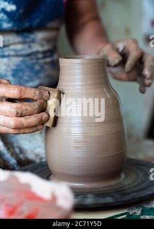 Mani di vasaio che fanno in creta su ruota di ceramica. Potter fa sulla ruota di ceramica Foto Stock