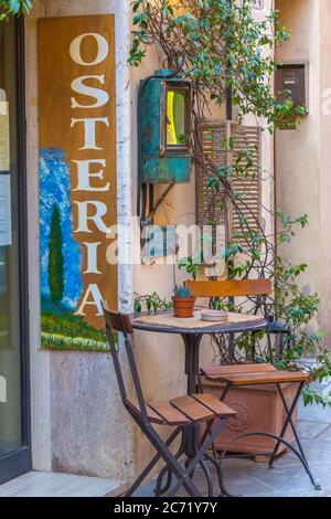La terrazza frontale dell'osteria locale presenta un tavolo e sedie tipici italiani e un ambiente carino a Montalcino, Italia. Foto Stock