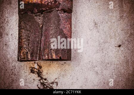 Un vecchio tubo vecchio di grondaia arrugginito vicino ad un muro Foto Stock