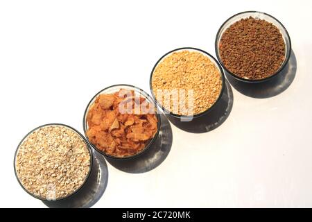 Raccolta di legumi (piselli di piccione, semi di Fenugreek, fiocchi di mais) in diverse ciotole isolate su sfondo bianco. Foto Stock