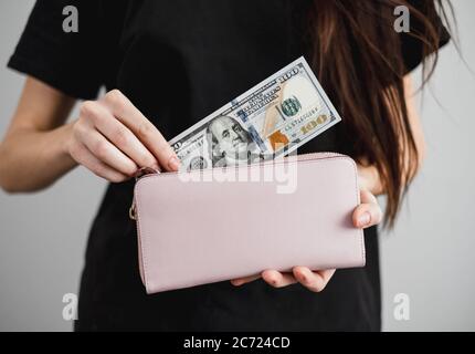 La giovane donna prende fuori i biglietti del dollaro di soldi da un portafoglio. Primo piano Foto Stock