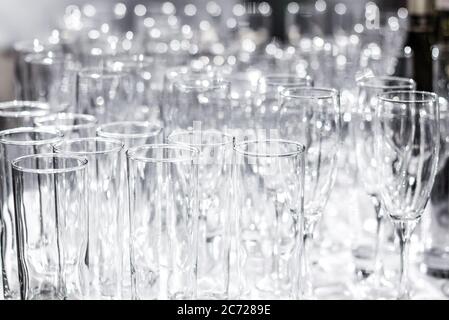 Molti bicchieri vuoti sul tavolo. Preparazione per un banchetto, una festa o un matrimonio. Sfondo sfocato. Foto Stock