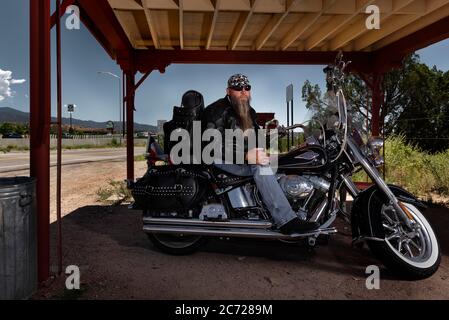 Santa Fe, New Mexico, Stati Uniti. 15 agosto 2019. Biker RON di Galveston TX a Camel Rock, che è un camionista per lavoro posato per fotografare la sua moto sotto l'area di riposo. Una donna che ha vissuto a New York dal 1924, si sposa, diventa madre di 3 ragazzi ed è un artista, realizza nei suoi anni 80 non può più vivere da sola. Suzanne Krieger sta per viaggiare dalla costa orientale di New York all'ovest americano in Colorado (USA), per diventare residente permanente al Veterans Center a Homelake, Colorado. 'Visiting Mum' è una serie fotografica che documenta il suo trasferimento in un Foto Stock