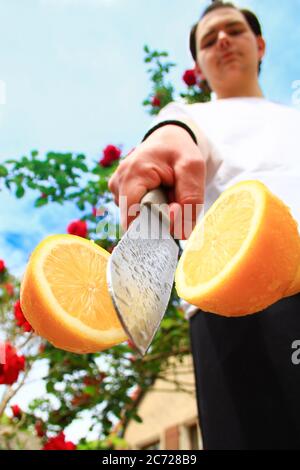 Un limone tagliato a metà da un coltello da cucina. Frutta piena di vitamine. Agrumi vegetariano o vegano. Sfondo deliberatamente sfocato. Foto Stock