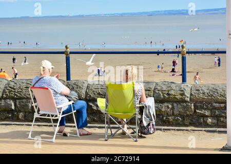 Barry Island, vale of Glam. / Galles - Giugno 24 2020: COVID-19 Social distanzing sulla spiaggia. Il sole è caldo e gli amici e le famiglie si siedono in gruppi 2 Foto Stock