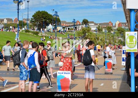 Barry Island, vale of Glam. / Galles - Giugno 24 2020: COVID-19 Social distanzing sulla spiaggia. Il sole è caldo e gli amici e le famiglie si siedono in gruppi 2 Foto Stock