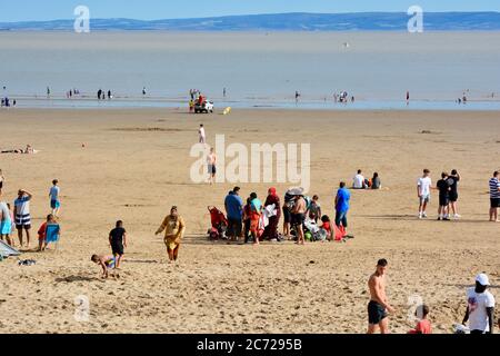Barry Island, vale of Glam. / Galles - Giugno 24 2020: COVID-19 Social distanzing sulla spiaggia. Il sole è caldo e gli amici e le famiglie si siedono in gruppi 2 Foto Stock