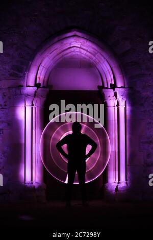 Sessione di pittura leggera in un luogo mistico. Forma circolare con una sciabola leggera. Silhouette di un uomo con una curva leggera dietro di lui. Architettura gotica. Foto Stock