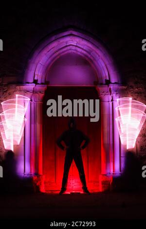 Sessione di pittura leggera in un luogo mistico. Forma circolare con una sciabola leggera. Silhouette di un uomo con una curva leggera dietro di lui. Architettura gotica. Foto Stock