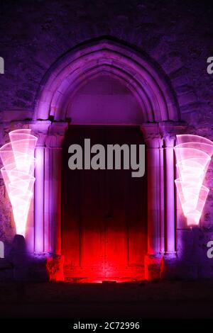 Sessione di pittura leggera in un luogo mistico la notte. Porta in legno di una chiesa con scultura gotica illuminata con led. Foto Stock