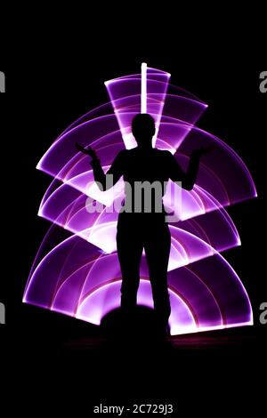 Silhouette di una donna davanti. Forma curva astratta, colore rosa con una sciabola chiara sullo sfondo. Effetti di luce in esposizione lunga. Foto Stock