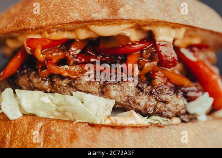 Volantino Burger. Hamburger di formaggio con carne alla griglia, formaggio, insalata e anelli di cipolla. Primo piano di delizioso hamburger fatto in casa su sfondo blu corteccia Foto Stock