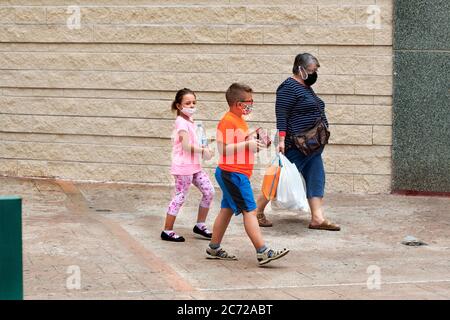 Donna e due bambini che lasciano il supermercato indossando maschere, Alcañiz, Spagna. Foto Stock
