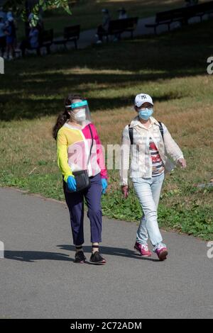 2 donne asiatiche americane su una camminata di esercitazione con sia le maschere chirurgiche che una, uno schermo del viso. A Kissena Park, Flushing, Queens, New York. Foto Stock