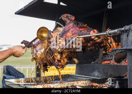 Porzionamento di maiale arrosto, affettamento di carne.. Maiale grigliato carbone tradizionale e fuoco. Il maiale viene arrostito intero su un fuoco aperto. Maiale sullo spiedo. Foto Stock