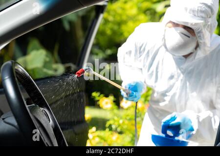 Primo piano di pulizia a spruzzo con alcool chimico all'interno dell'auto per disinfettare e decontaminare il coronavirus covid-19 da un detergente specializzato che indossa il prodotto personale Foto Stock