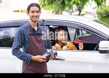 Ritratto di donna asiatica rendere mobile pagamento contactless tecnologia per l'ordine di alimentari online e drive thru servizio. Guida attraverso e cibo online i Foto Stock