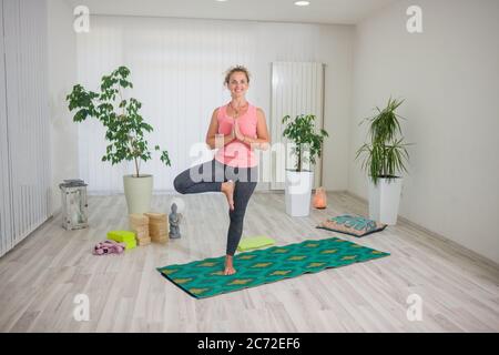 una giovane donna di mezza età che pratica yoga, al coperto in studio di yoga, Foto Stock