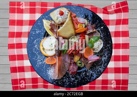 Cucina tradizionale italiana. Primo piano di antipasti mediterranei misti o antipasto e tapas con verdure al prosciutto e cancro su un piatto nero. Vista dall'alto. Foto Stock