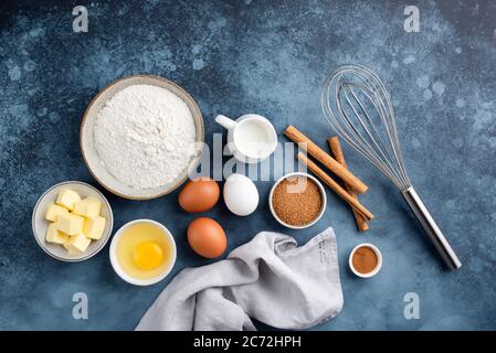Ingredienti per la cottura di torte, dolci o pane dolce su fondo blu testurizzato. Vista dall'alto degli ingredienti per cucinare Foto Stock