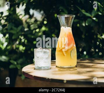 Bicchiere di limonata con ghiaccio su tavolino nel cortile estivo. Foto Stock