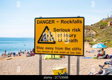 Grande segno giallo di avvertimento delle cascate alle scogliere del mare a Burton Bradstock, l'inizio della spiaggia di Chesil, sulla costa Jurassic di Dorset, Regno Unito Foto Stock