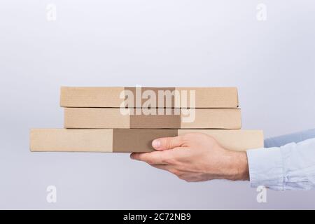 Scatole per pizza in mani maschili. Sfondo bianco. Vista laterale. Consegna tramite corriere. Foto Stock