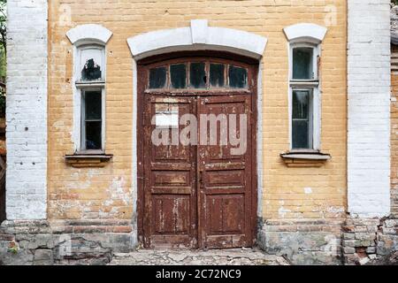 Chiusura di un vecchio edificio con porta in legno e muro di mattoni. Foto Stock