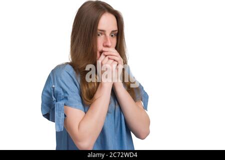 Una ragazza con capelli lunghi in un abito blu. Isolata su sfondo bianco, tiene le mani sul viso, un'espressione spaventata sul viso Foto Stock