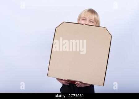 Bambino che tiene una scatola di pizza e ride, dai capelli lonesti con una scatola in mano. Consegna pizza. Foto Stock