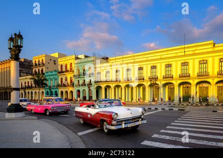 Auto classiche ed edifici colorati nel centro di l'Avana al tramonto Foto Stock