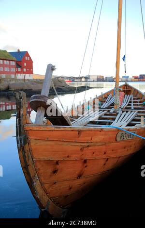 Un tradizionale scalo faroese barca docking nel porto di Torshavn con case in legno con tetto di erba in Tinganes in background.Torshavn.Streymoy.Faroe Islands.Territory della Danimarca Foto Stock