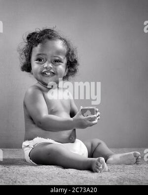 1940 ANNI 1950 SORRIDENTE AFROAMERICANO BABY GIRL SEDUTA UPMHOLDING BLOCK - N452 HAR001 HARS AFROAMERICANI AFROAMERICANI NERI ETNIA PANNOLINI SORRIDE GIOIOSA CRESCITA GIOVANILE BAMBINA NERA E BIANCA HAR001 VECCHIO STILE AFROAMERICANI Foto Stock