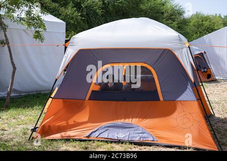 Matamoros, Messico. 13 luglio 2020. Una coppia aspetta nella loro tenda di isolamento. Attualmente ci sono 23 persone che aspettano in isolamento per essere testate o per i risultati dei loro test del coronavirus. 3 dei residenti del campo hanno provato positivi per il virus. Ci sono circa 1,500 persone che vivono in tende all'interno di una zona recintata fuori del parco mentre attendono le loro audizioni di asilo negli Stati Uniti d'America. Credit: Cripps/Alamy Live News Foto Stock