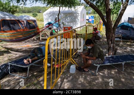 Matamoros, Messico. 13 luglio 2020. Diverse persone sono viste in attesa in isolamento. Attualmente ci sono 23 persone che aspettano in isolamento per essere testate o per i risultati dei loro test del coronavirus. 3 dei residenti del campo hanno provato positivi per il virus. Ci sono circa 1,500 persone che vivono in tende all'interno di una zona recintata fuori del parco mentre attendono le loro audizioni di asilo negli Stati Uniti d'America. Credit: Cripps/Alamy Live News Foto Stock