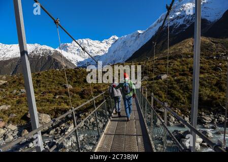 Queenstown. 13 luglio 2020. Due escursionisti attraversano un ponte sospeso al Parco Nazionale di Aoraki/Mount Cook, nell'Isola del Sud della Nuova Zelanda, il 13 luglio 2020. Il Parco Nazionale Aoraki/Mount Cook è composto da 19 cime che si trovano ad almeno 3000 metri sul livello del mare, oltre al Ghiacciaio Tasman e a molti laghi glaciali. Credit: Guo Lei/Xinhua/Alamy Live News Foto Stock