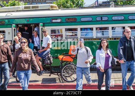 San Francisco California, l'Embarcadero, tram elettrico, trolley pole, ferrovia passeggeri, fermata autobus, uomo uomini maschio, donna donne, pedicab, taxi, passenge Foto Stock