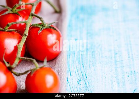 Pomodori ciliegini su fondo blu spazzolone Foto Stock