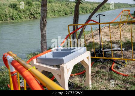 Matamoros, Messico. 13 luglio 2020. I tubi dell'acqua corrono lungo il bordo dell'area di isolamento per fornire acqua nella zona di isolamento. Attualmente ci sono 23 persone che aspettano in una zona di isolamento per essere testate o per i risultati dei loro test del coronavirus. 3 dei residenti del campo hanno provato positivi per il virus. Ci sono circa 1,500 persone che vivono in tende all'interno di una zona recintata fuori del parco mentre attendono le loro audizioni di asilo dagli Stati Uniti d'America. Credit: SOPA Images Limited/Alamy Live News Foto Stock