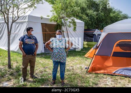 Matamoros, Messico. 13 luglio 2020. Una coppia indossava maschere di fronte visto in attesa fuori della loro tenda di isolamento. Attualmente ci sono 23 persone che aspettano in una zona di isolamento per essere testate o per i risultati dei loro test del coronavirus. 3 dei residenti del campo hanno provato positivi per il virus. Ci sono circa 1,500 persone che vivono in tende all'interno di una zona recintata fuori del parco mentre attendono le loro audizioni di asilo dagli Stati Uniti d'America. Credit: SOPA Images Limited/Alamy Live News Foto Stock